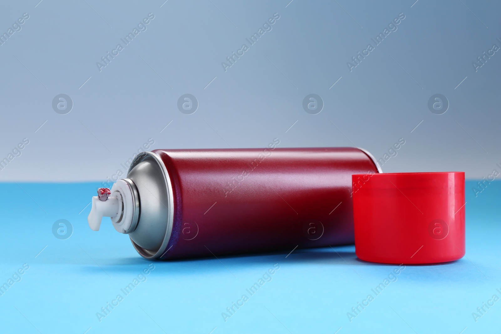 Photo of Red spray paint can on light blue background