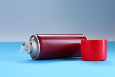 Red spray paint can on light blue background