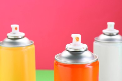 Many spray paint cans on color background, closeup