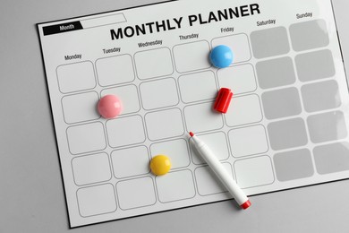 Timetable. Planner with bright magnets and red felt pen on grey table, top view