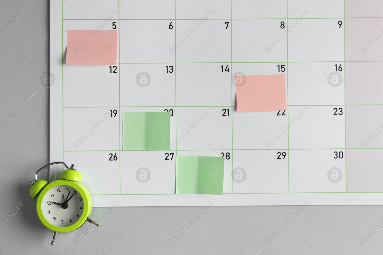 Photo of Timetable. Planner with sticky notes and alarm clock on grey table, top view