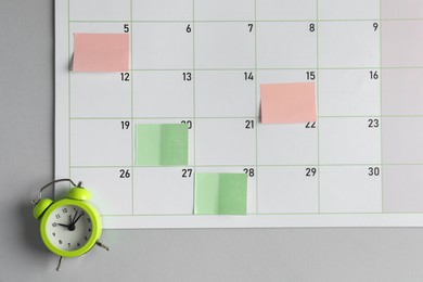 Photo of Timetable. Planner with sticky notes and alarm clock on grey table, top view