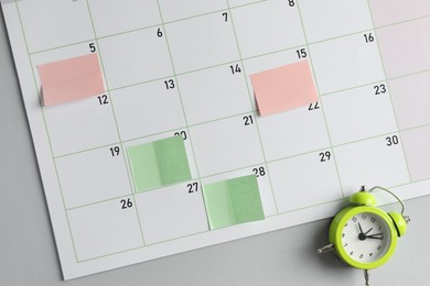 Photo of Timetable. Planner with sticky notes and alarm clock on grey table, top view