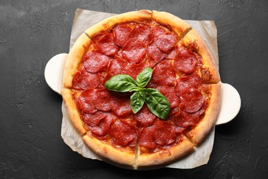 Photo of Tasty pepperoni pizza on black textured table, top view