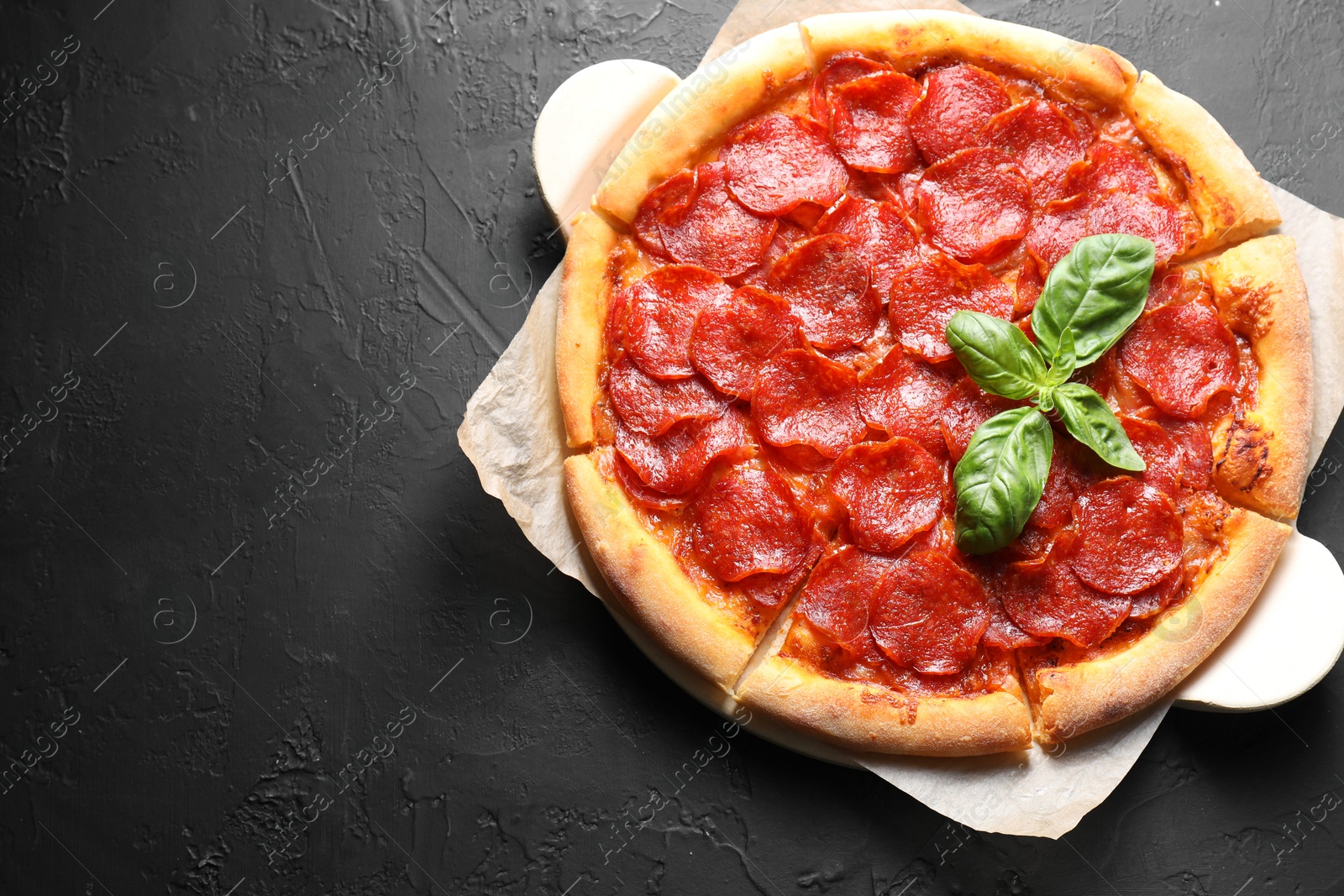 Photo of Tasty pepperoni pizza on black textured table, top view. Space for text