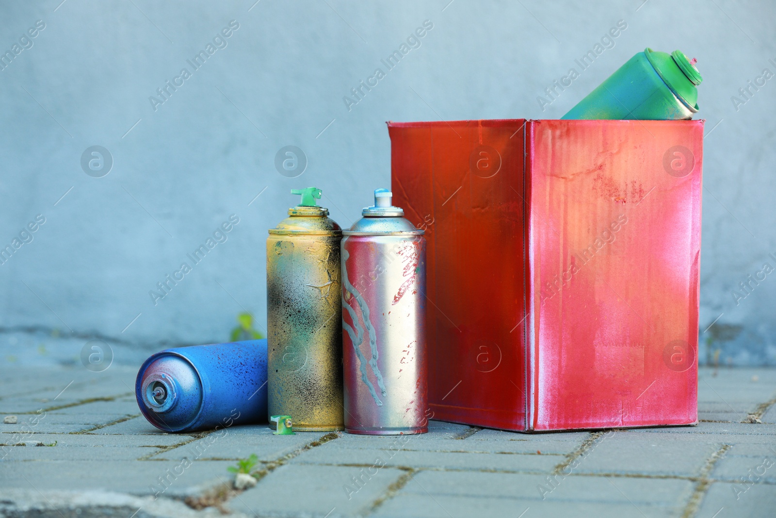 Photo of Many spray paint cans and red cardboard box outdoors