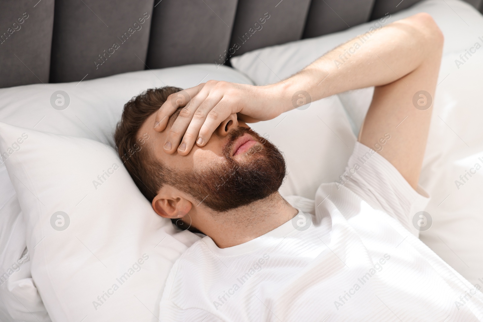 Photo of Handsome young man waking up in bed at morning