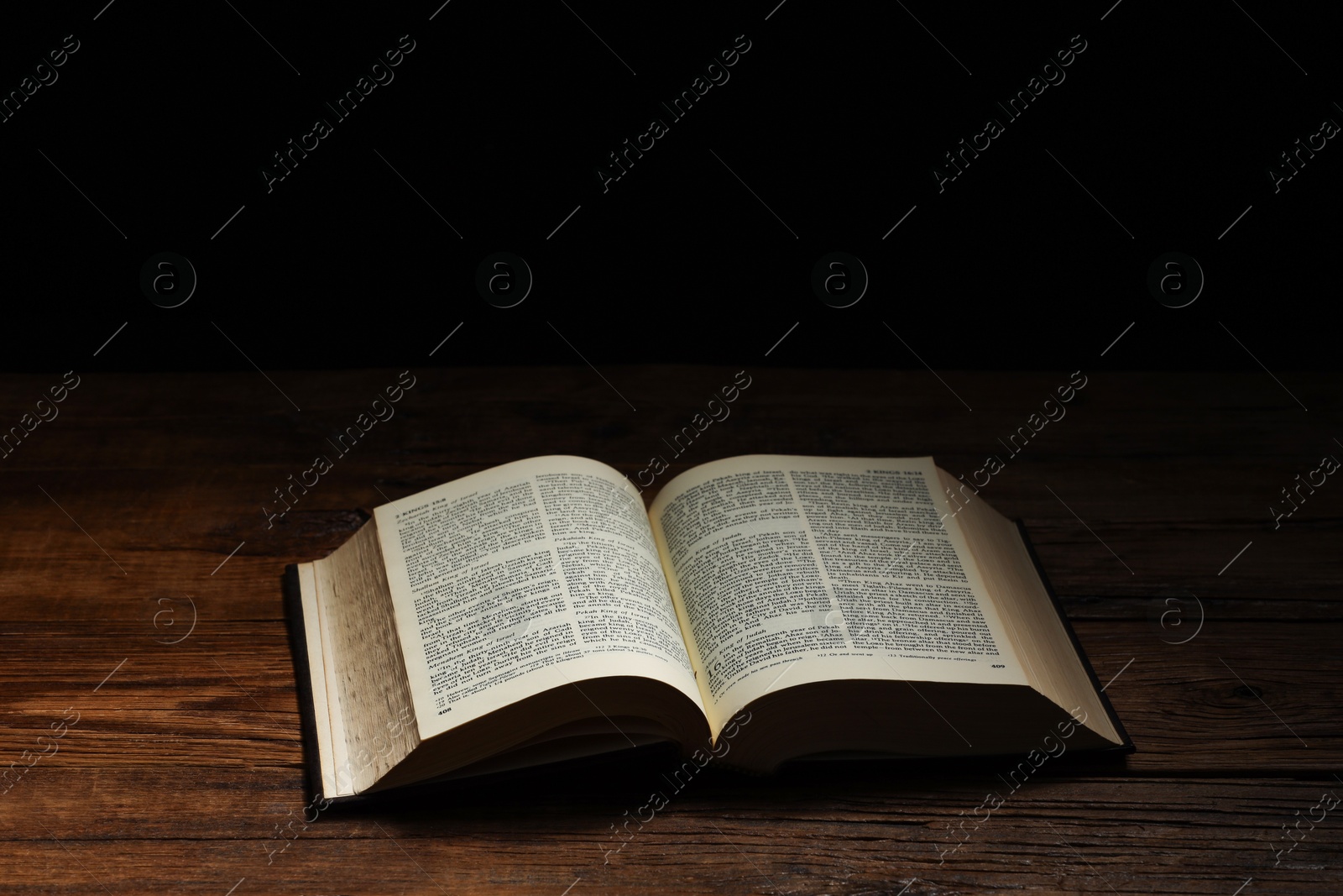 Photo of Bible on wooden table against black background, space for text. Religion of Christianity