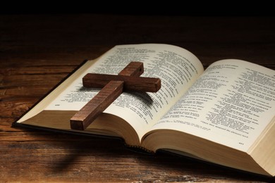 Photo of Bible and cross on wooden table, closeup. Religion of Christianity