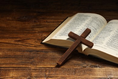 Photo of Bible and cross on wooden table, closeup with space for text. Religion of Christianity