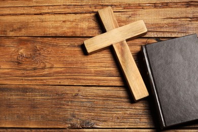 Photo of Bible and cross on wooden table, flat lay with space for text. Religion of Christianity