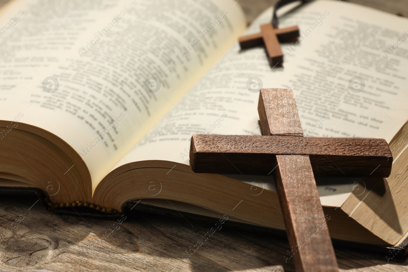 Photo of Bible and crosses on wooden table, closeup. Religion of Christianity