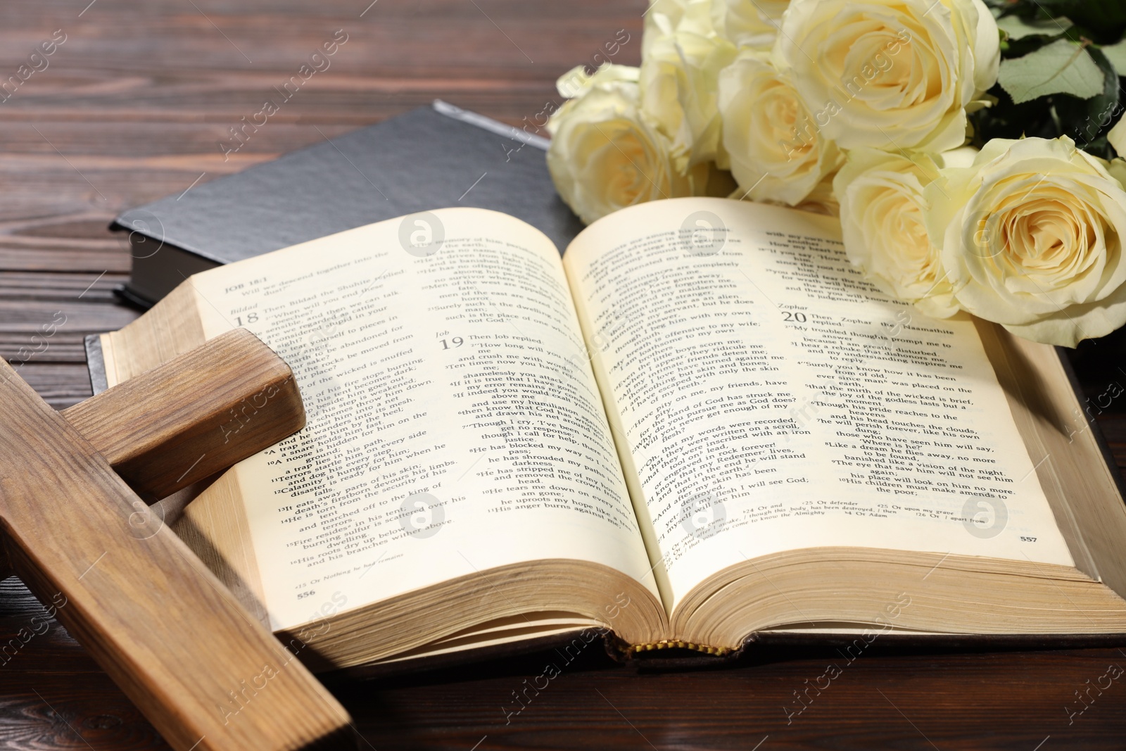 Photo of Bibles, cross and roses on wooden table, closeup. Religion of Christianity