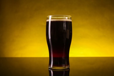 Photo of Glass of beer with froth on dark table, closeup