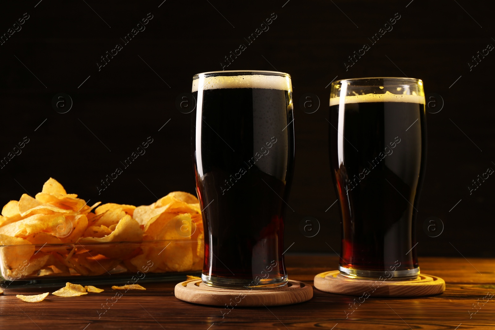 Photo of Glasses of beer and potato chips on wooden table