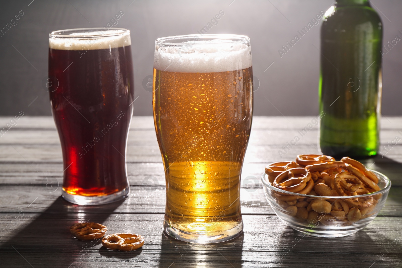 Photo of Glasses of beer and pretzel crackers on grey wooden table