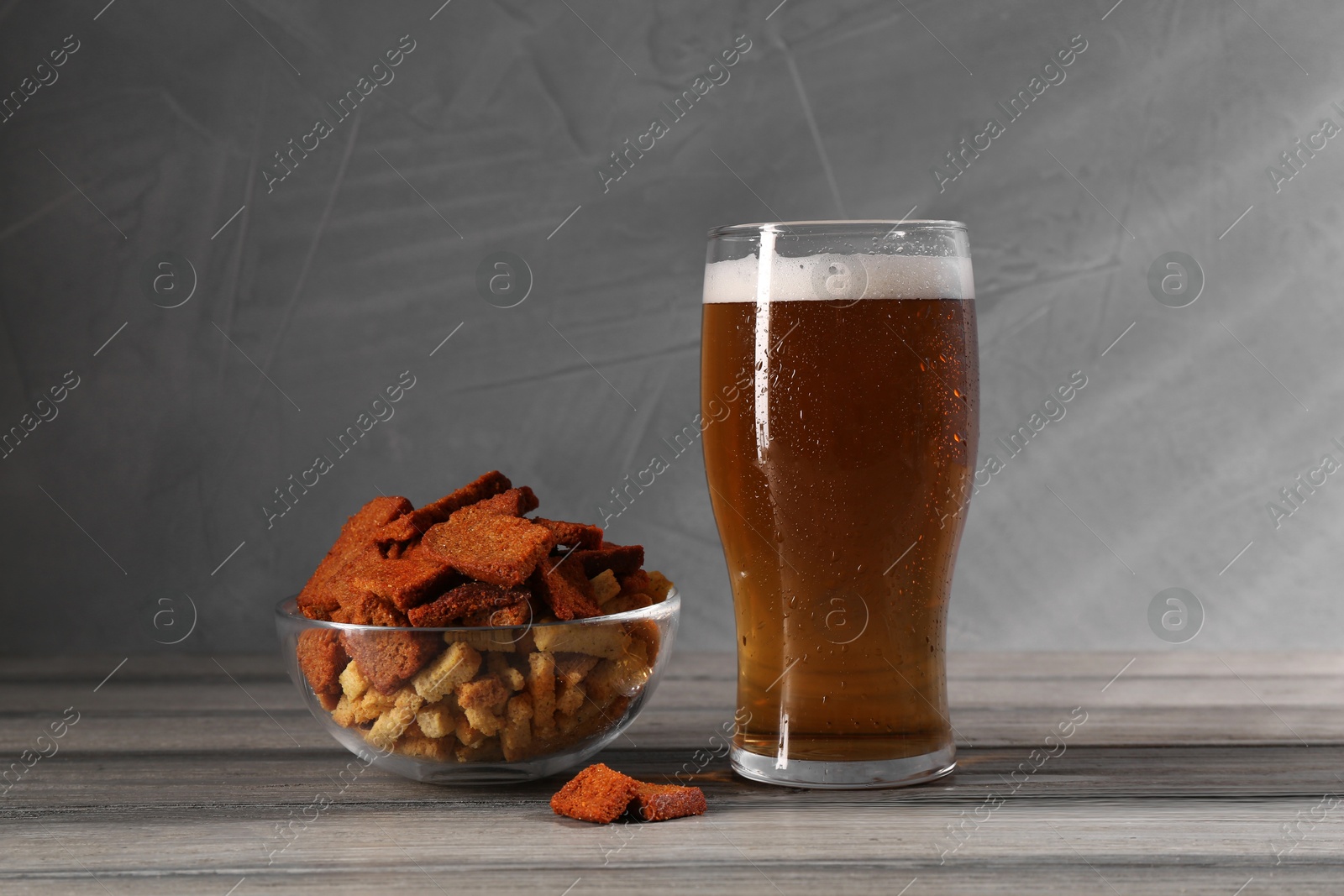 Photo of Glass of beer and rusks on grey wooden table