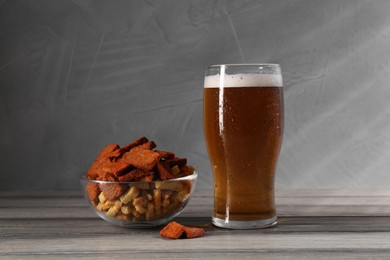 Photo of Glass of beer and rusks on grey wooden table