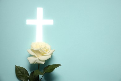 Shining cross and rose flower on turquoise background. Religion of Christianity