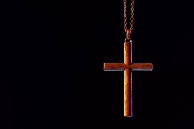 One cross with chain on black background, space for text. Religion of Christianity