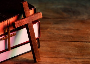 Photo of Crosses and stack of books on wooden table, closeup with space for text. Religion of Christianity