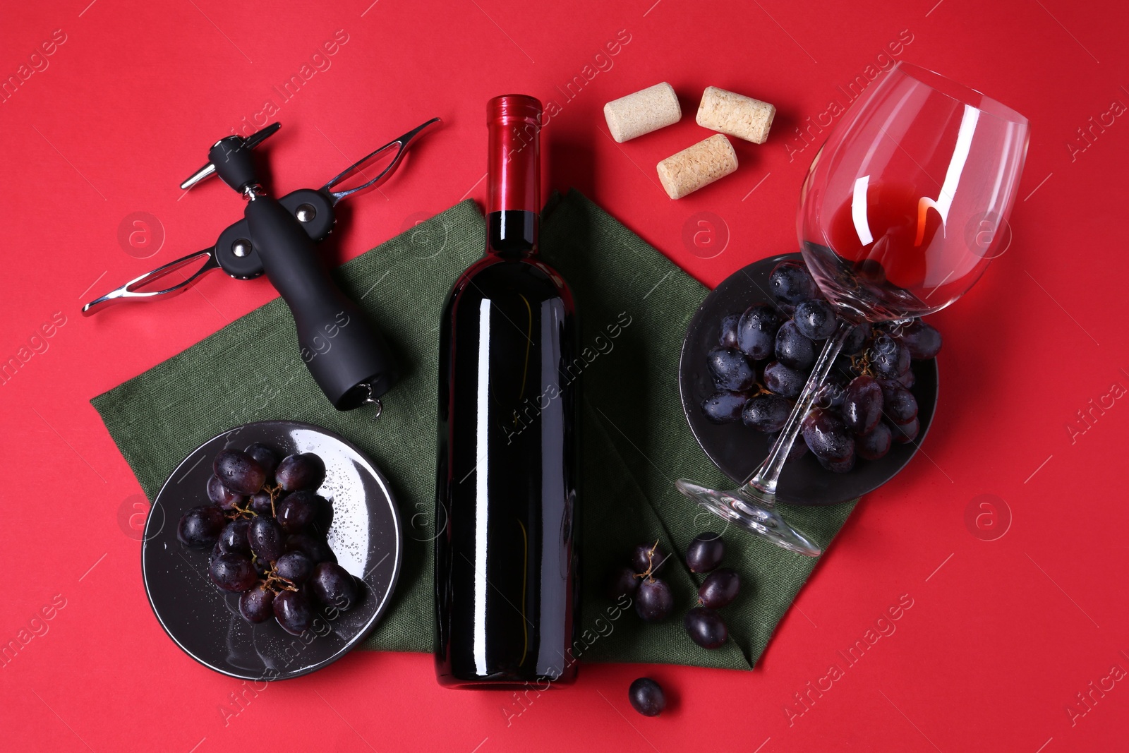 Photo of Flat lay composition with wing corkscrew and bottle of wine on red background