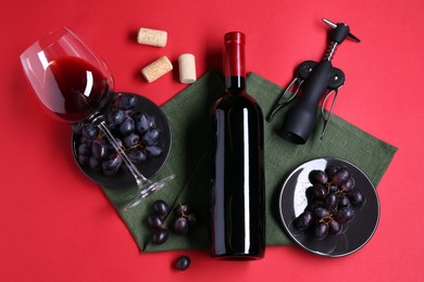 Flat lay composition with wing corkscrew and bottle of wine on red background