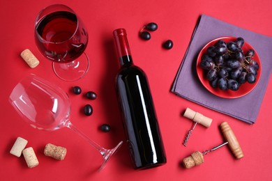 Photo of Flat lay composition with wooden corkscrews and bottle of wine on red background