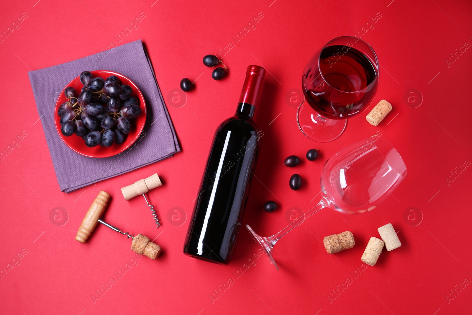 Photo of Flat lay composition with wooden corkscrews and bottle of wine on red background