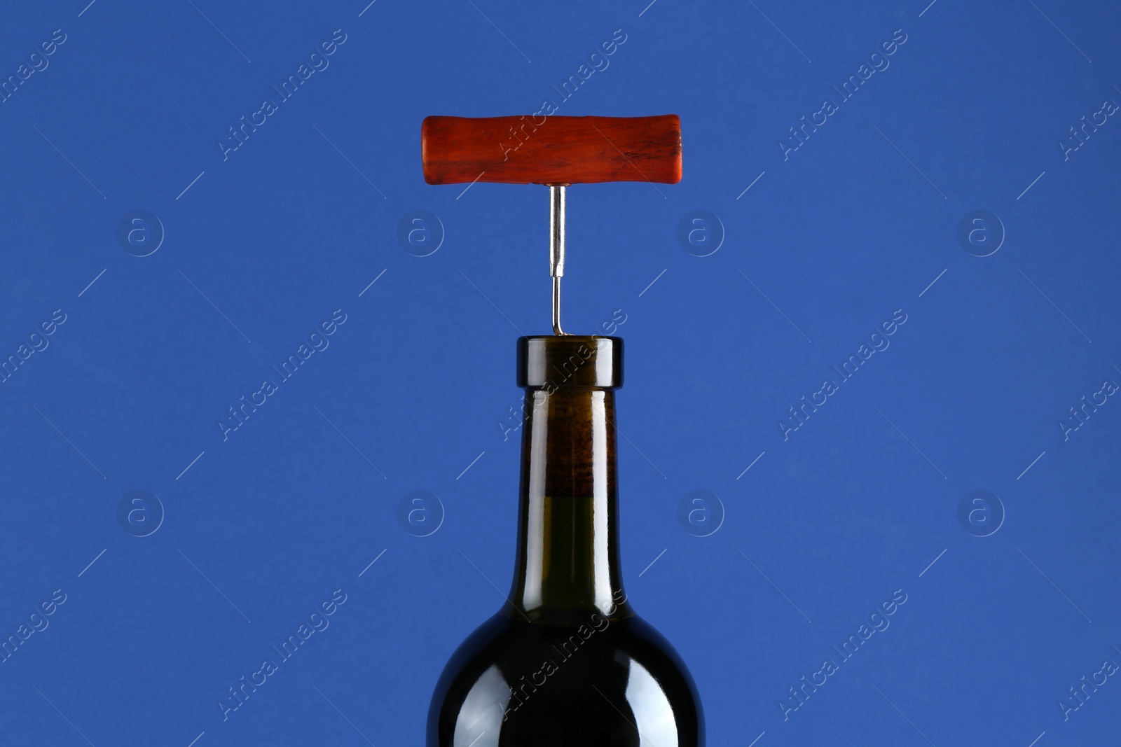 Photo of Bottle with corkscrew on blue background, closeup