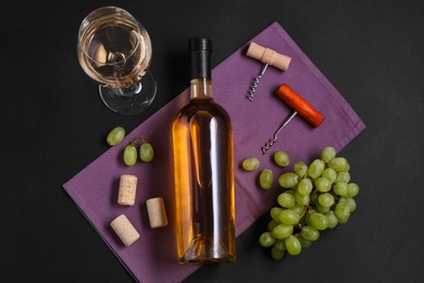 Photo of Corkscrews, wine, grapes and corks on black background, flat lay