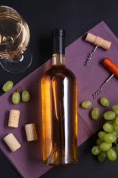 Corkscrews, wine, grapes and corks on black background, flat lay