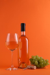 Photo of Wine, corkscrew and fresh grapes on orange background