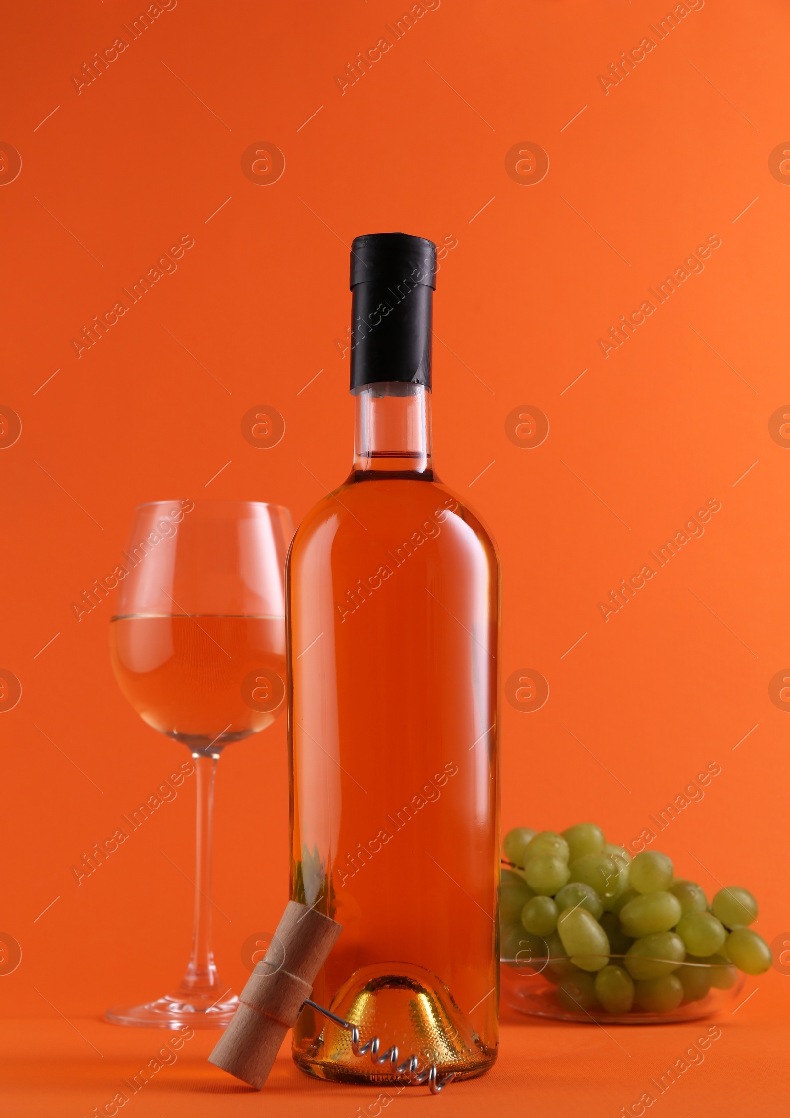 Photo of Wine, corkscrew and fresh grapes on orange background