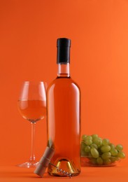 Photo of Wine, corkscrew and fresh grapes on orange background