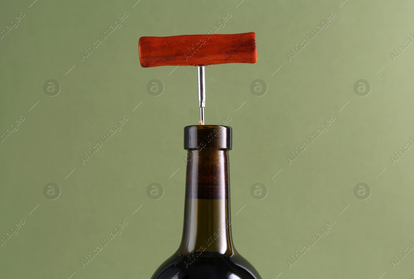 Photo of Wine bottle with corkscrew on olive background, closeup