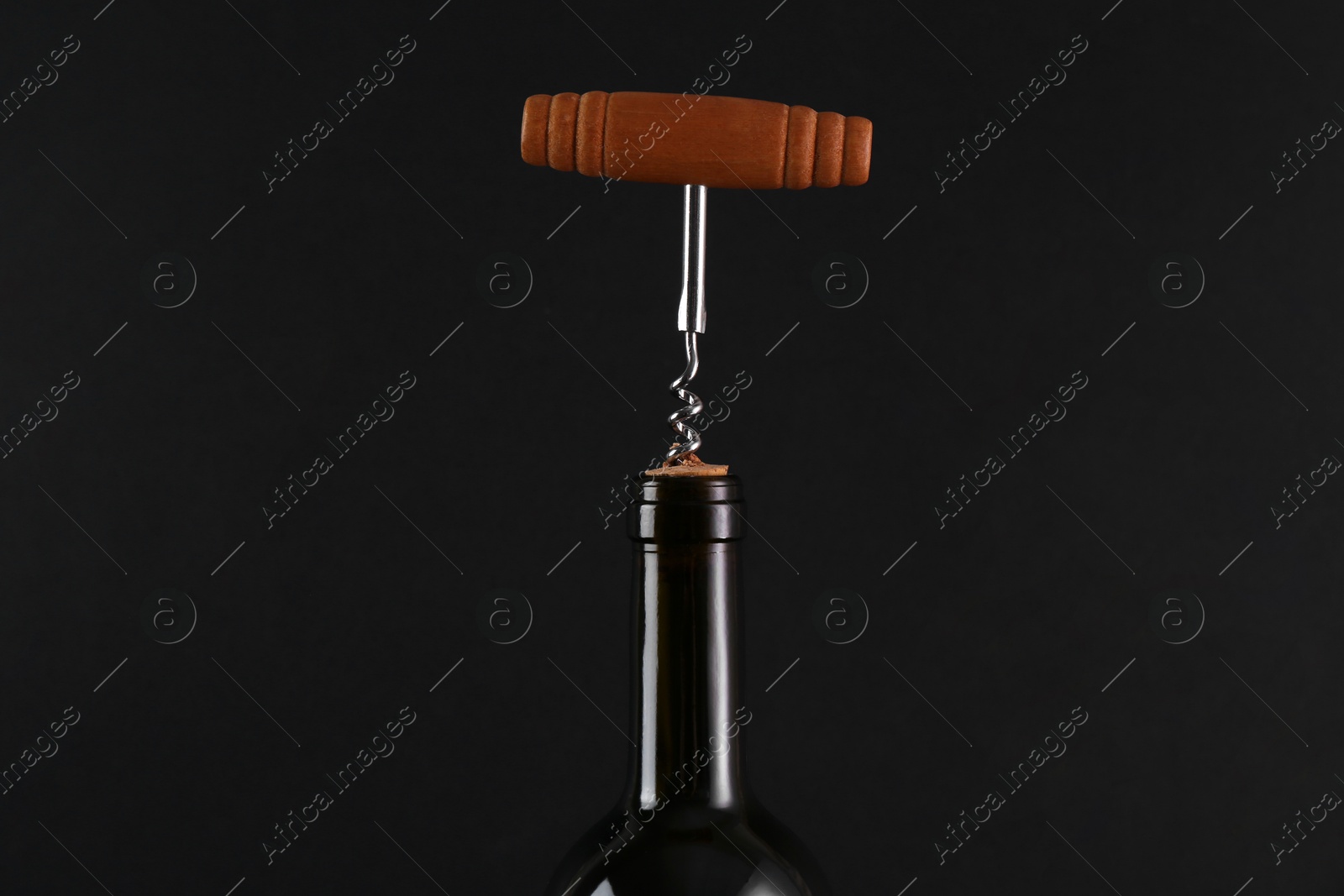 Photo of Wine bottle with corkscrew on black background