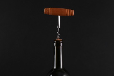 Photo of Wine bottle with corkscrew on black background