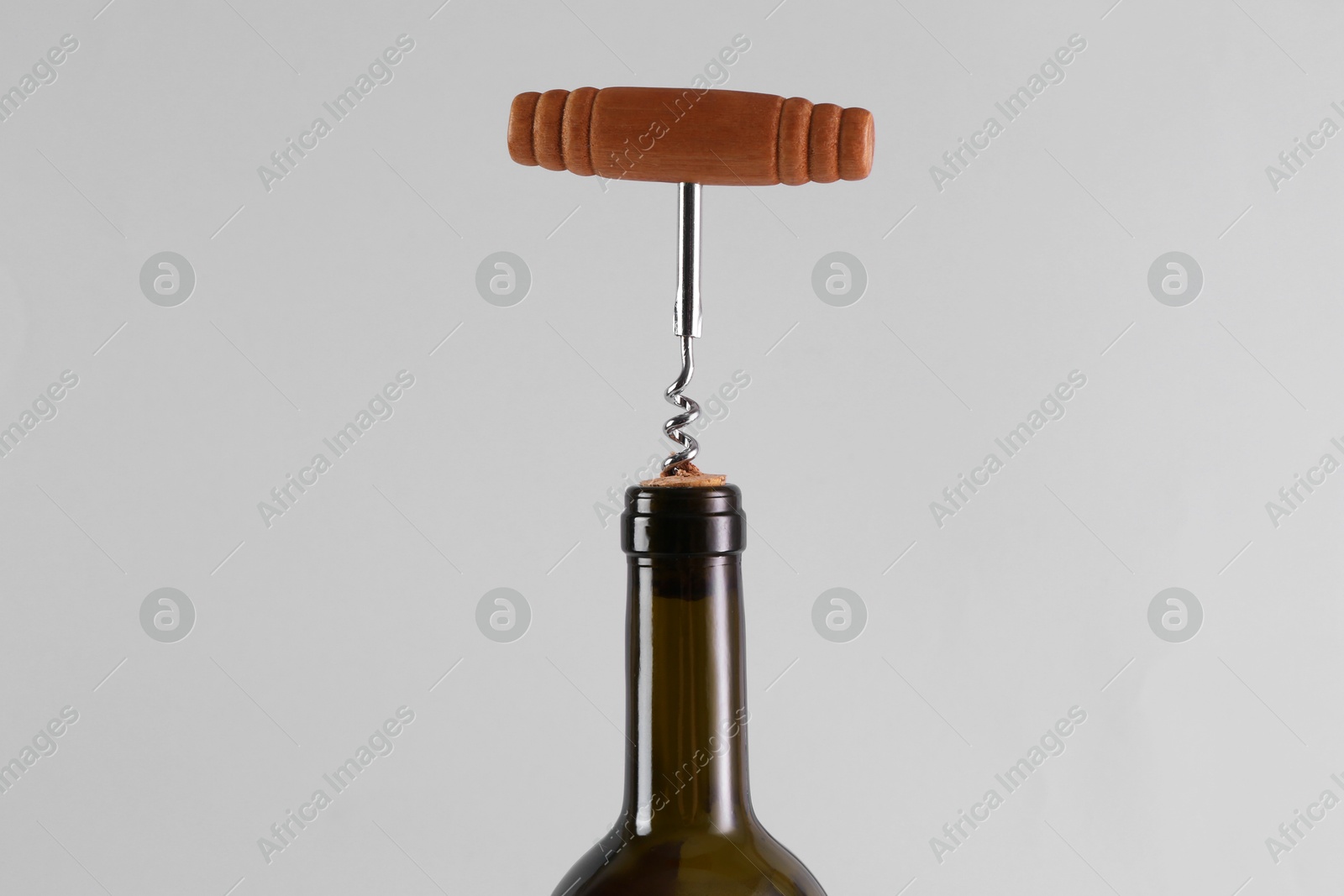 Photo of Wine bottle with corkscrew on grey background