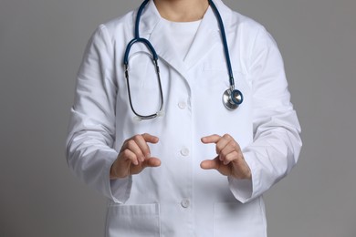 Doctor holding something on grey background, closeup