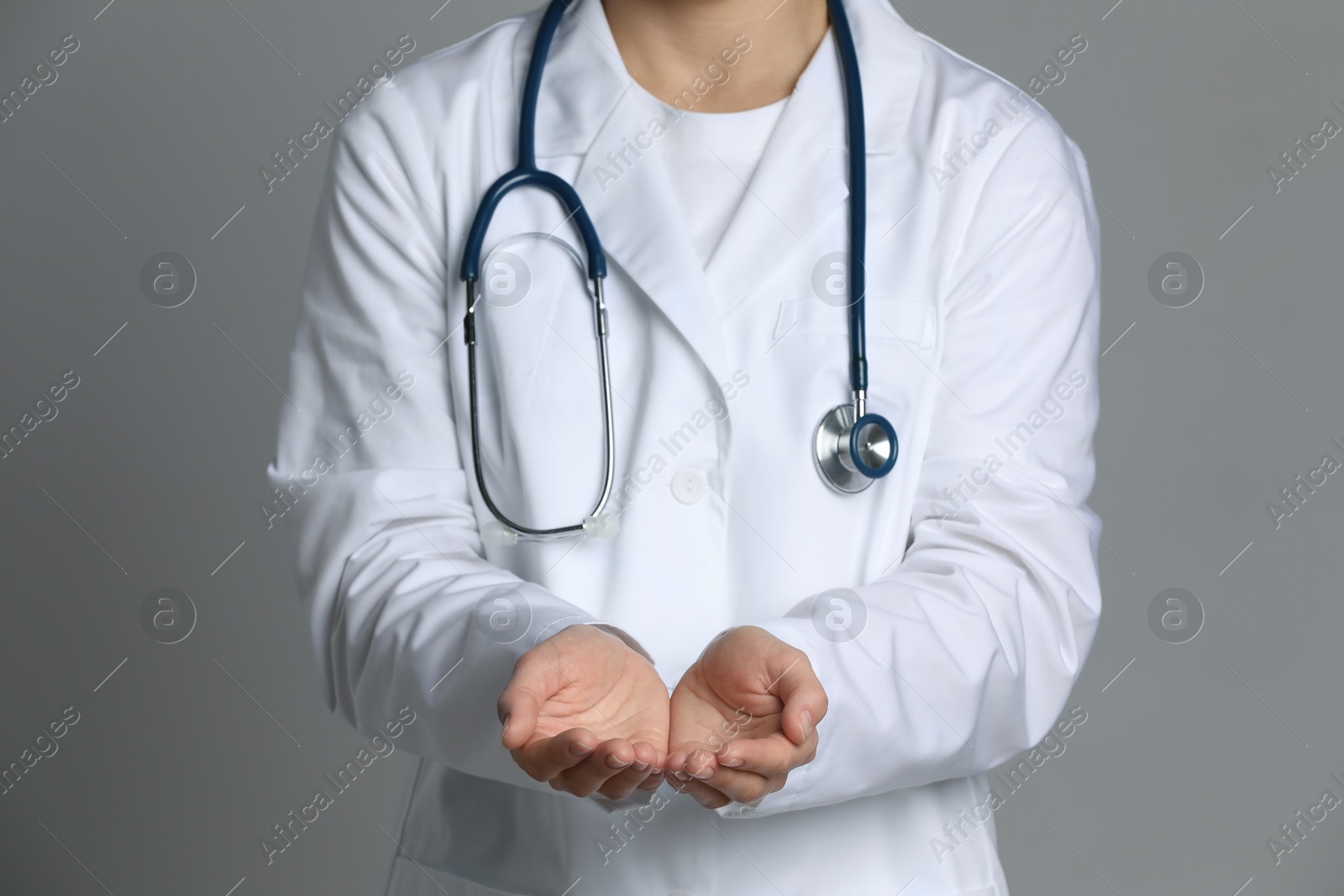 Photo of Doctor holding something on grey background, closeup