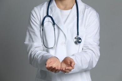 Doctor holding something on grey background, closeup