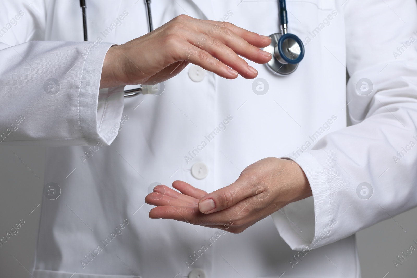 Photo of Doctor holding something on grey background, closeup