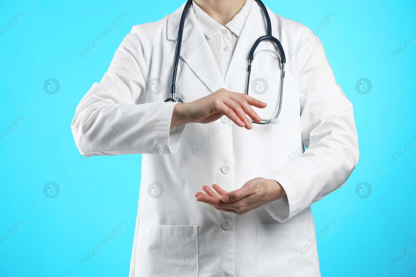 Photo of Doctor holding something on light blue background, closeup