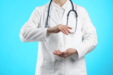 Doctor holding something on light blue background, closeup