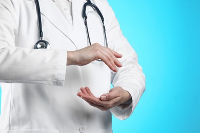 Doctor holding something on light blue background, closeup