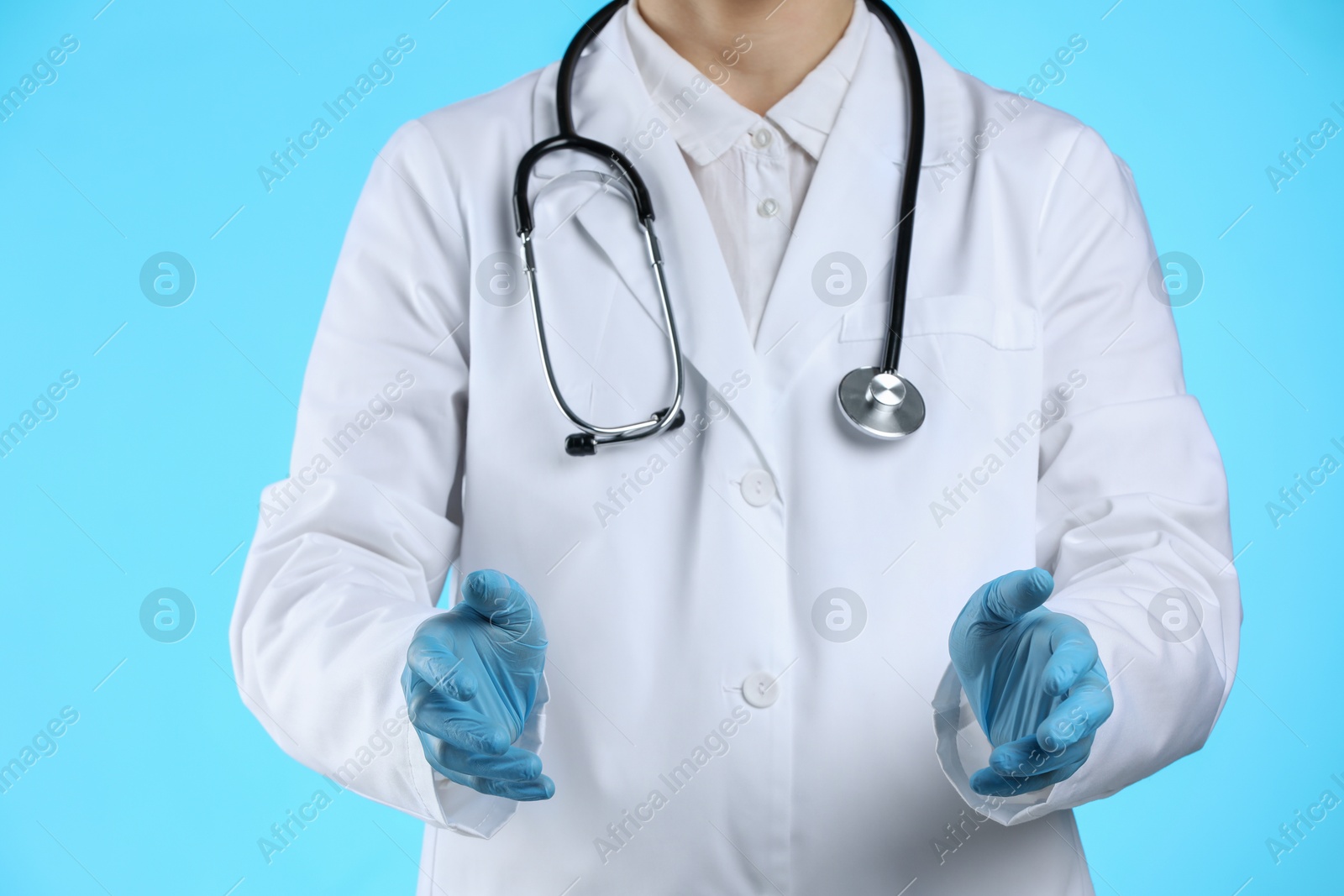 Photo of Doctor holding something on light blue background, closeup