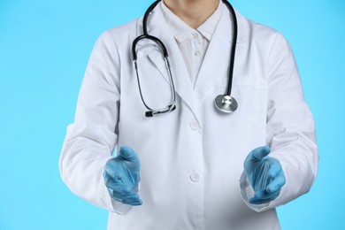 Doctor holding something on light blue background, closeup