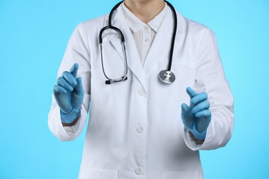 Doctor holding something on light blue background, closeup