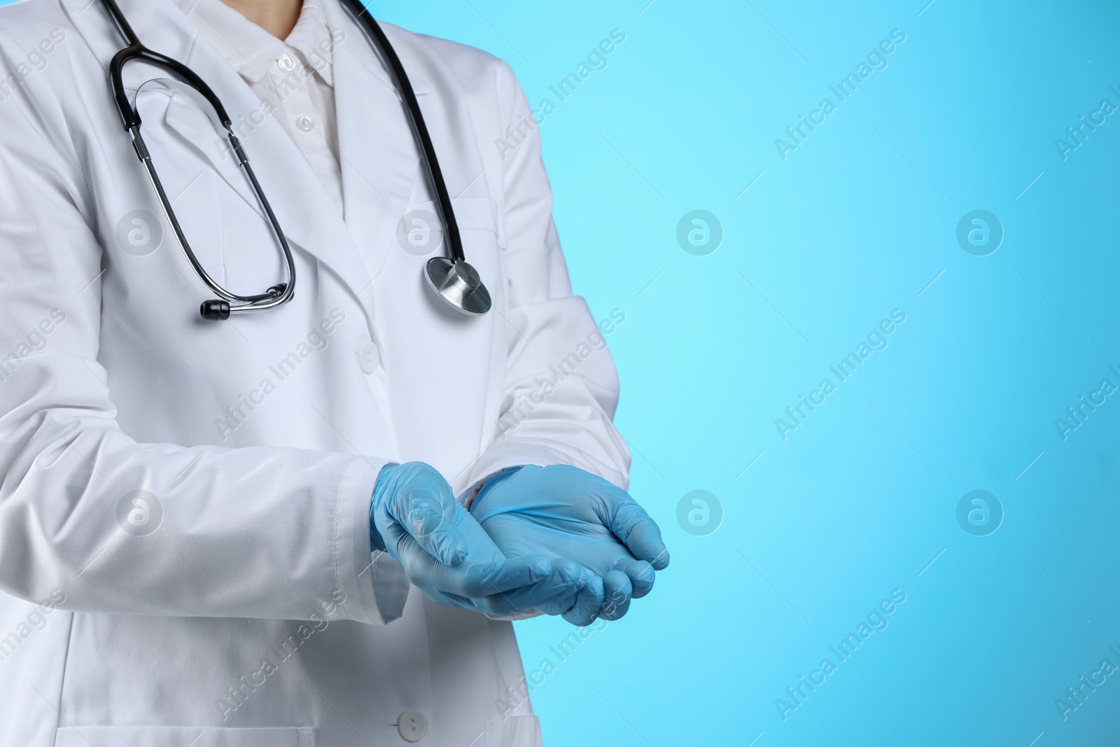 Photo of Doctor holding something on light blue background, closeup. Space for text